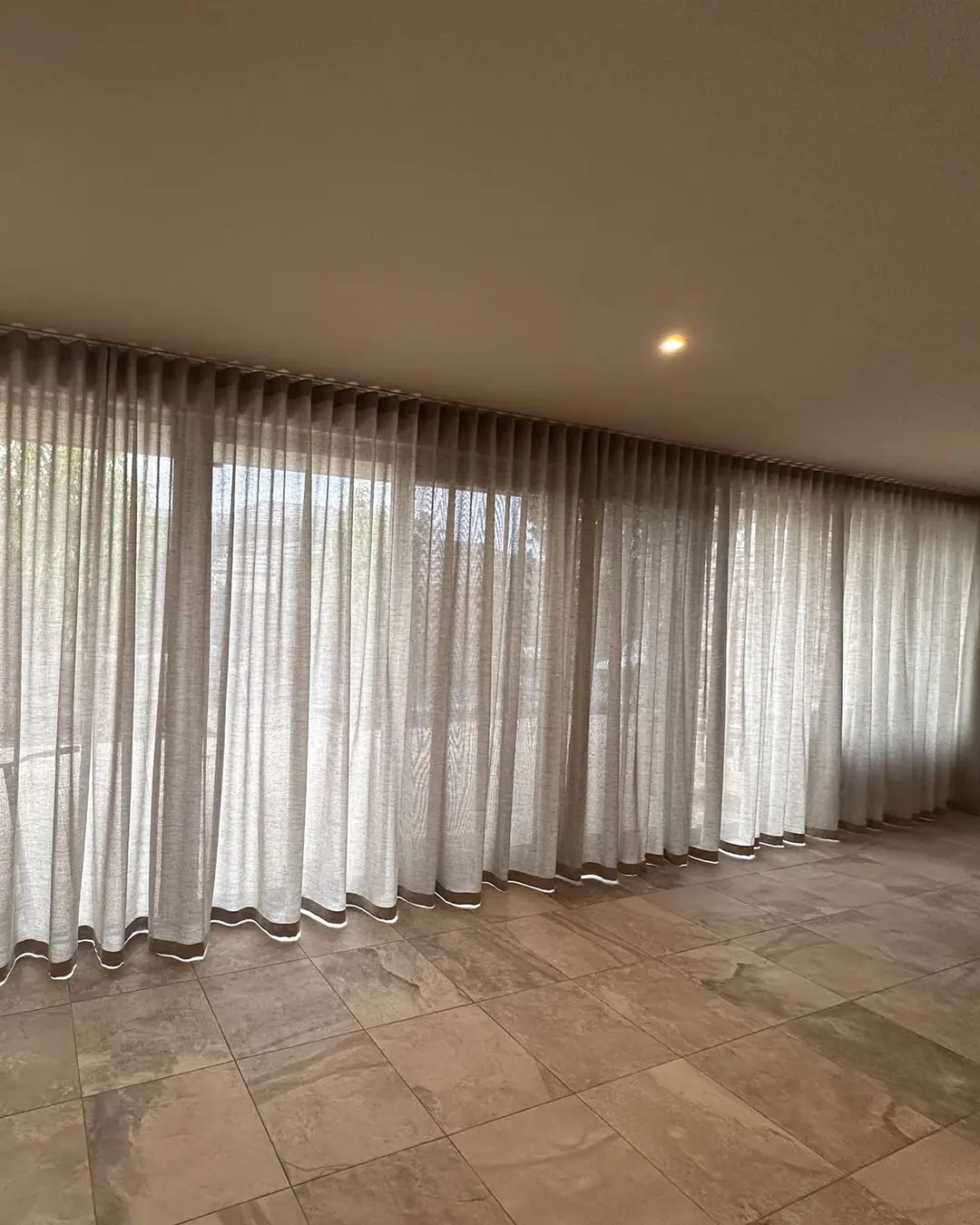 Full-height sheer curtains fitted across a wide living-room opening