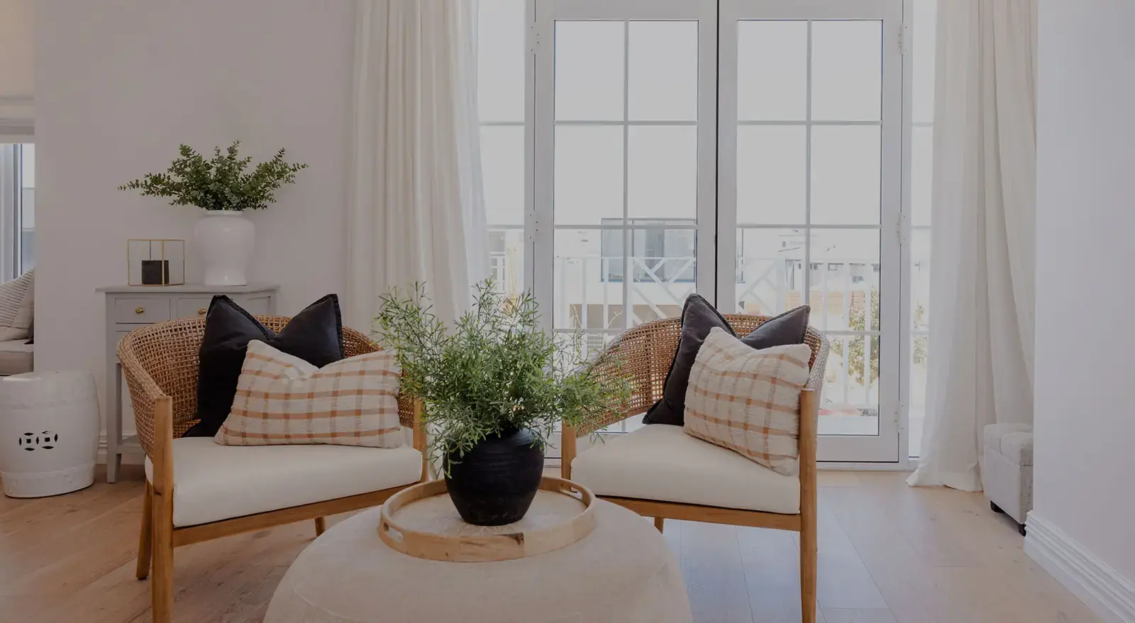 Bright living room with full-length sheer curtains framing French doors.